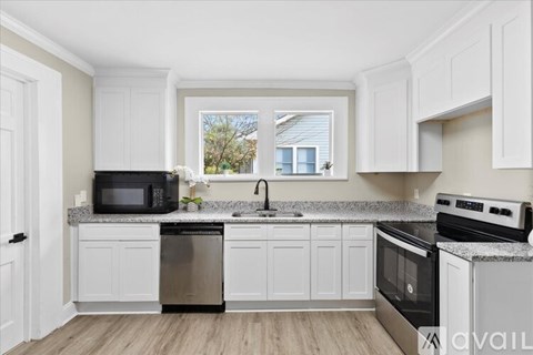 A kitchen with white cabinets and a window.
