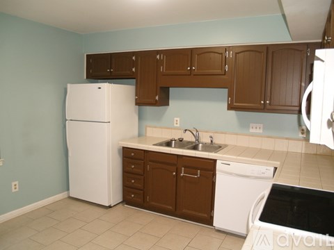 A kitchen with a white refrigerator and brown cabinets.