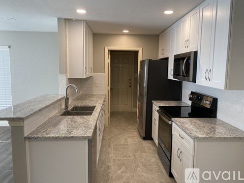A kitchen with granite countertops and white cabinets.