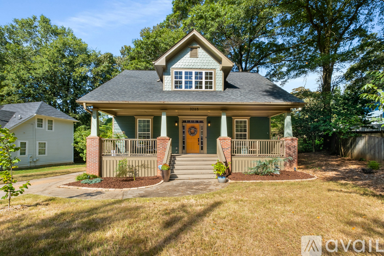 A house with a front porch and a brown door is surrounded by greenery.