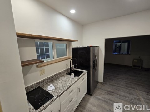 A kitchen with a black stove top and a black fridge.