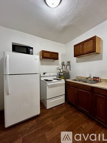 A kitchen with a white refrigerator, a white stove, and wooden cabinets.
