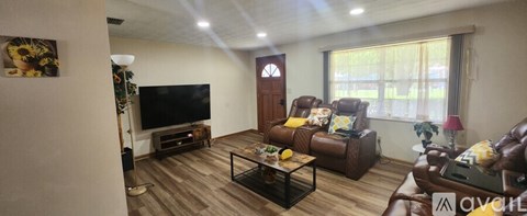 A living room with a brown leather couch and a flat screen TV.