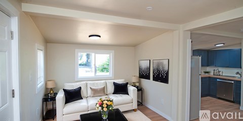 A living room with a white couch and a vase of flowers on the coffee table.