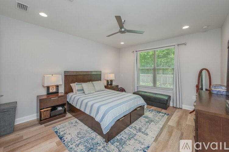 A bedroom with a bed, nightstand, and window.