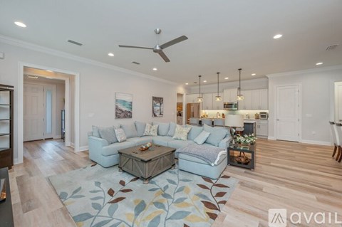 A living room with a grey couch and a rug with leaves design.