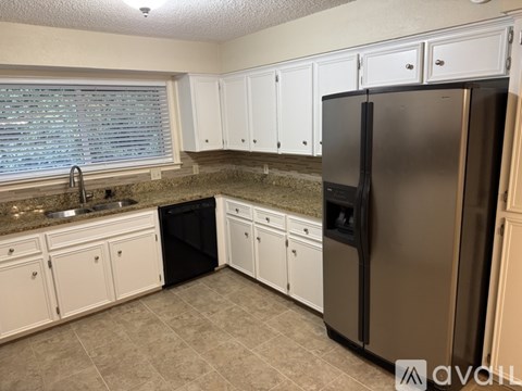 A kitchen with white cabinets and a black refrigerator.