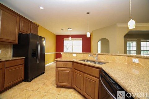 A kitchen with a black refrigerator and wooden cabinets.