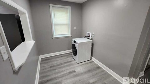 A room with a window, a white radiator, and a wooden floor.