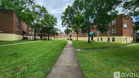A grassy area with a walkway separates two rows of red brick apartment buildings.