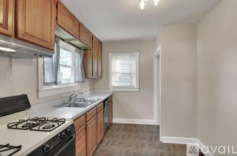 A kitchen with a stove, sink, and cabinets.
