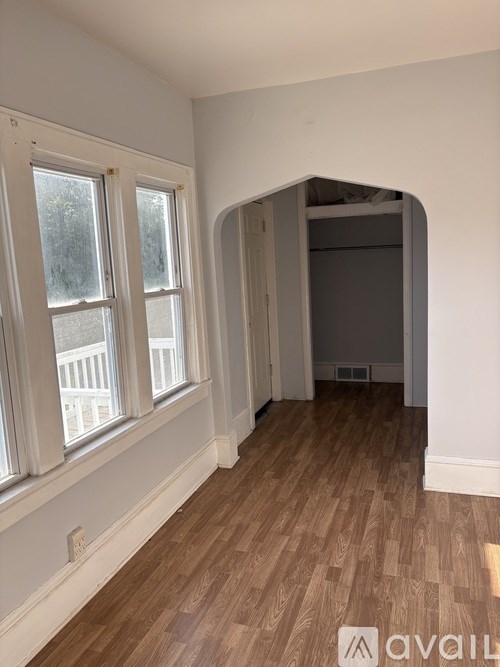 A room with wooden flooring and a window with a view of a balcony.