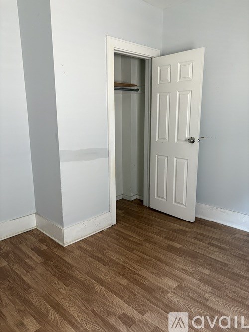 A room with a white door and wooden floor.