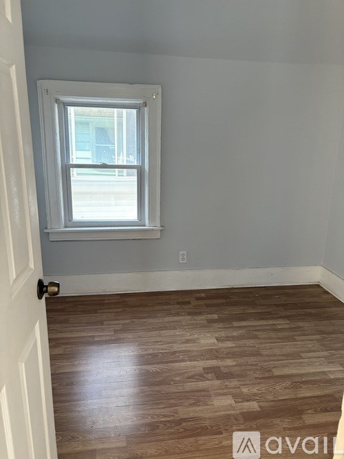 A room with a window and wooden flooring.