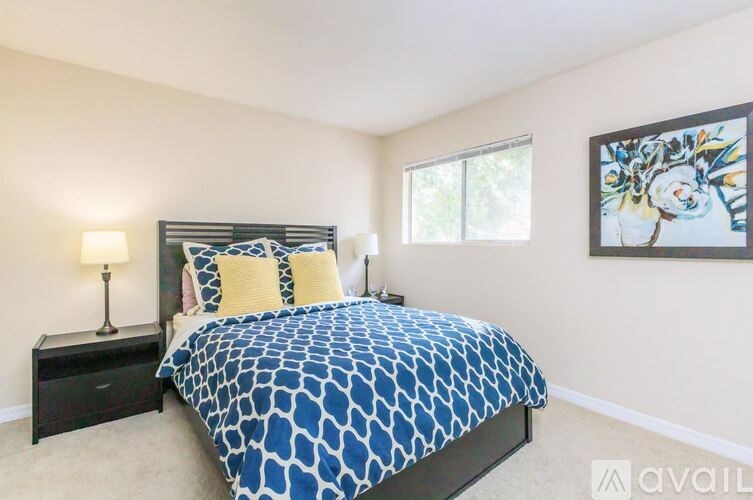 A bedroom with a bed, nightstand, and a painting on the wall.