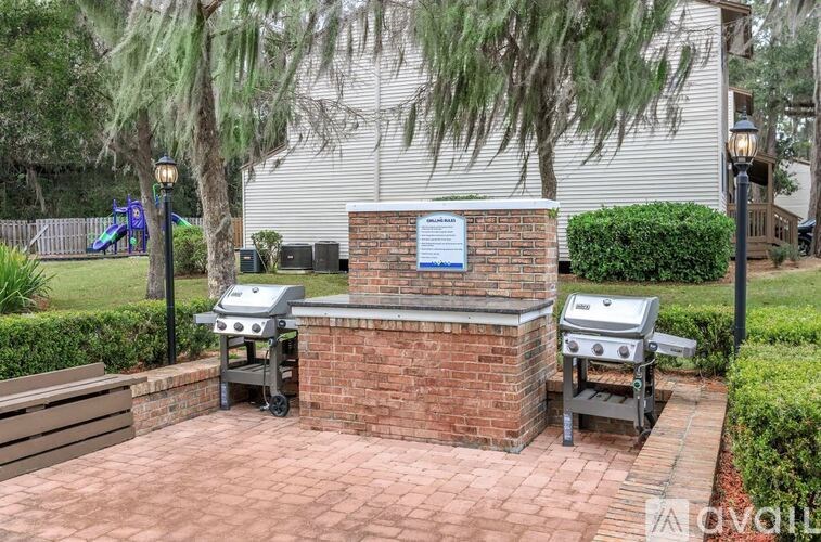 A brick BBQ grill area with a sign in front of a house.