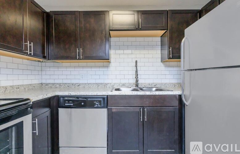 A kitchen with dark brown cabinets and a white fridge.