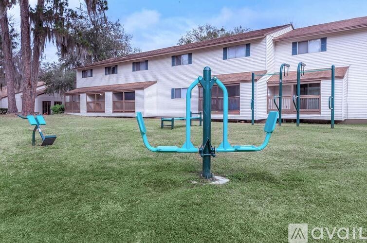 A playground with a teal swing set in front of a white apartment building.