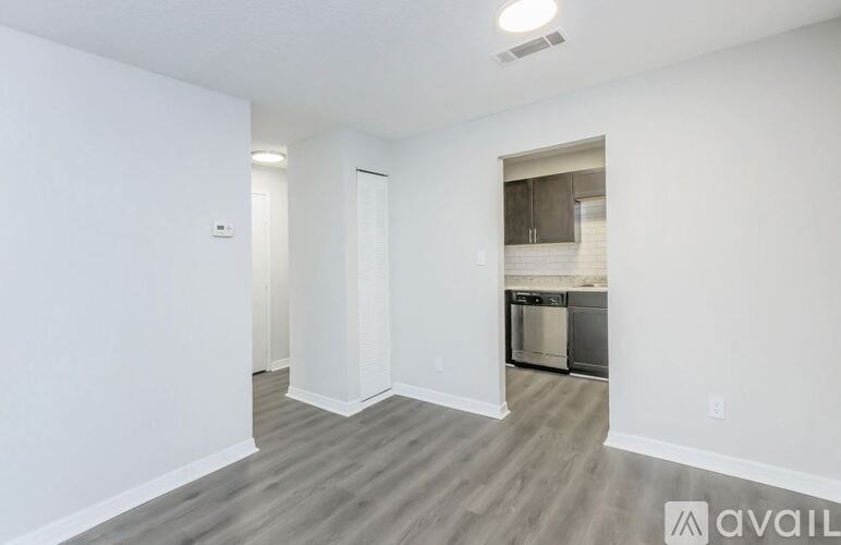 A spacious living room with a kitchen in the background.