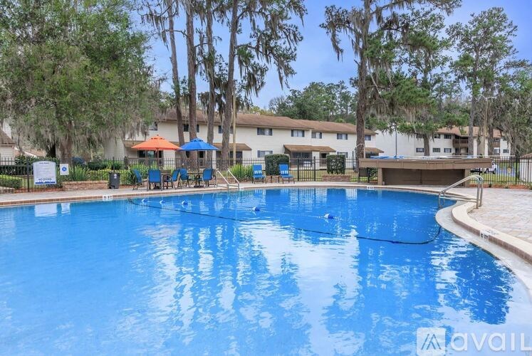 A swimming pool surrounded by trees and a building in the background.