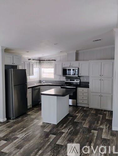 A kitchen with a black fridge and a black countertop.