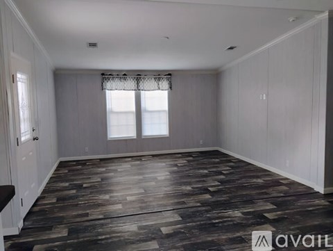 A spacious room with wooden flooring and white walls.