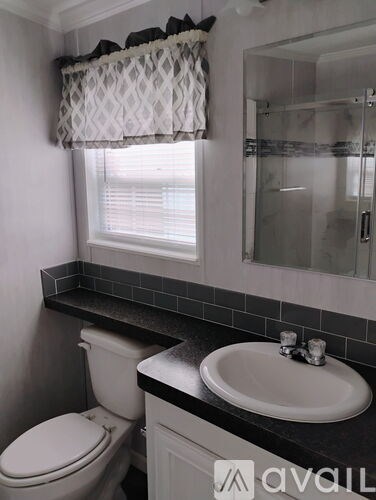 A bathroom with a toilet, sink, and window.