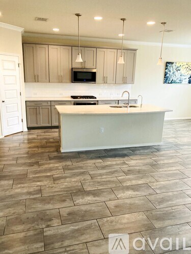 A kitchen with a white island in the middle of a tiled floor.