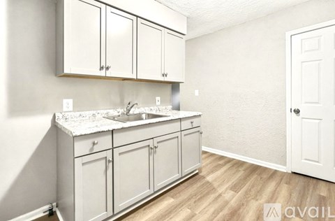 A kitchen with white cabinets and a marble countertop.