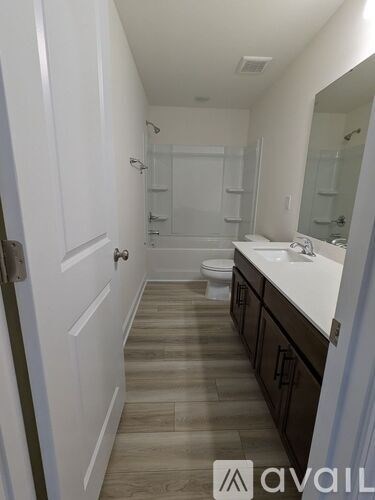 A bathroom with a toilet, sink, and mirror.