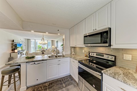 A kitchen with white cabinets and a granite countertop.