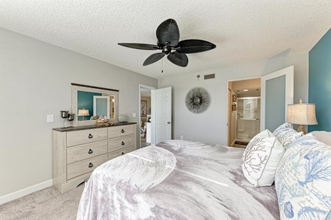 A bedroom with a large bed and a ceiling fan.