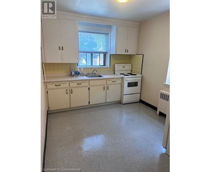 A small kitchen with white cabinets and a window.
