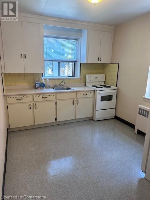 A small kitchen with white cabinets and a window.