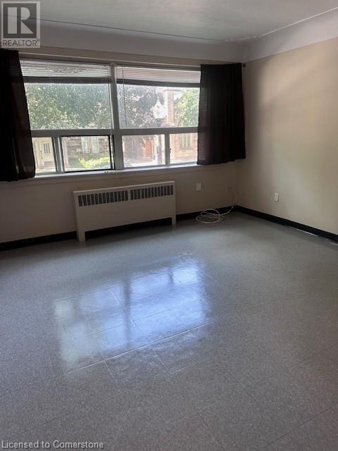 A room with a window and a radiator on the floor.