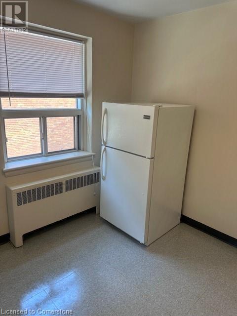 A white refrigerator in a room with a window and a radiator.