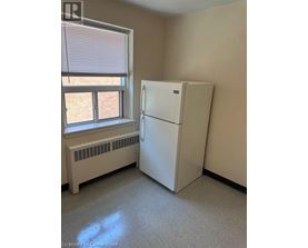 A white refrigerator in a room with a window and a radiator.