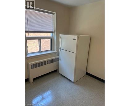 A white refrigerator in a room with a window and a radiator.