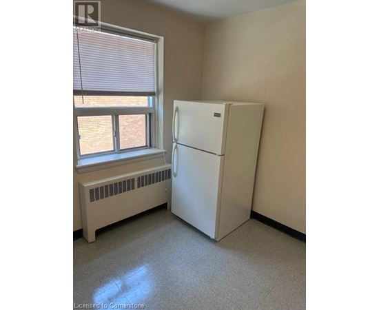 A white refrigerator in a room with a window and a radiator.