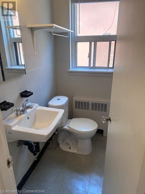 A bathroom with a toilet, sink, and window.