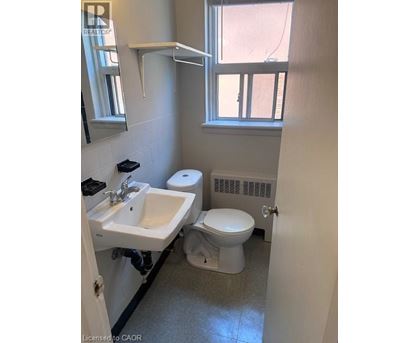 A bathroom with a toilet, sink, and window.