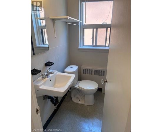 A bathroom with a toilet, sink, and window.
