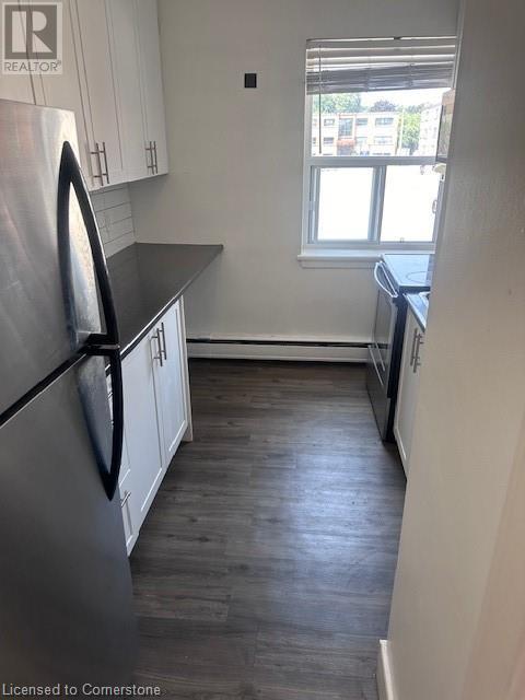 A kitchen with a stainless steel refrigerator and wooden floors.