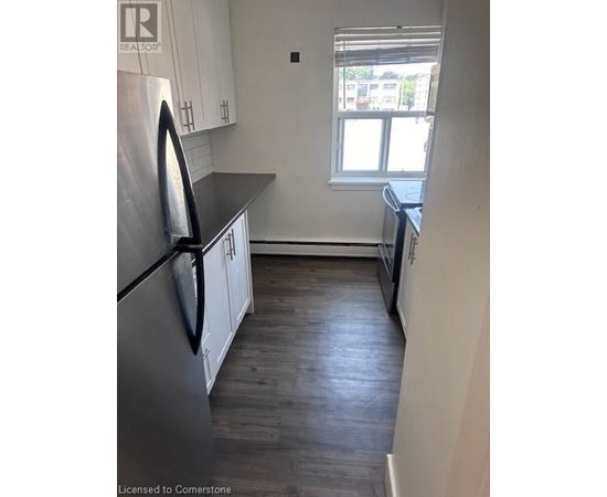 A kitchen with a stainless steel refrigerator and wooden floors.
