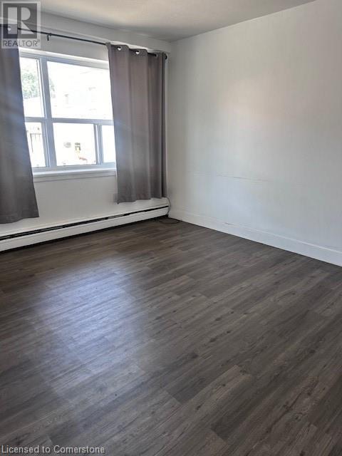 A room with wooden flooring and a window with curtains.