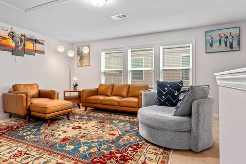 A living room with a rug and three chairs.