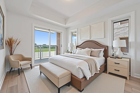 A bedroom with a large bed, a chair, and a view of the outside.