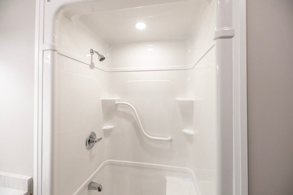 A white shower stall with a door and a shower head.