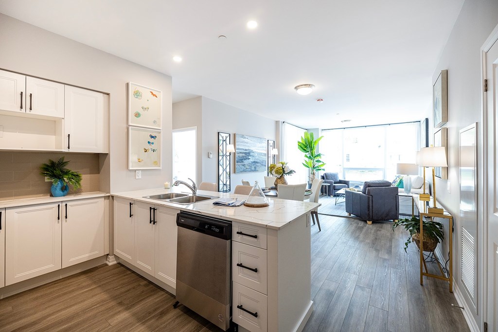 A modern kitchen with a dishwasher, sink, and a large window.