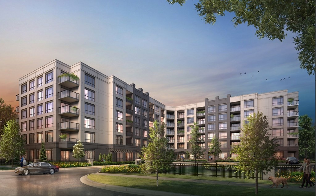 A modern apartment complex with a car driving on the street in front.